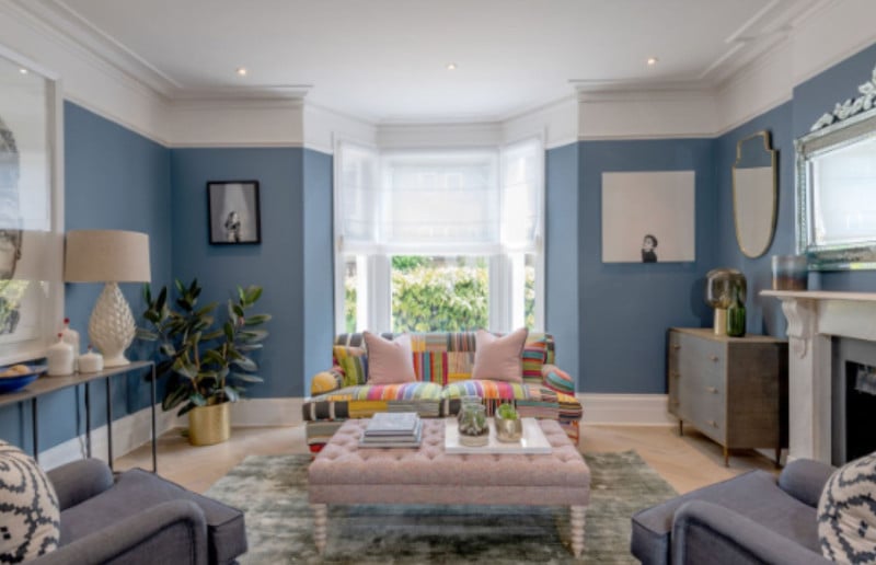 colour scheme for house, sitting room with dusty blue walls pairing nicely with a colourful sofa, adding to the vibrancy in the room.